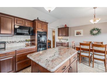 Spacious kitchen featuring custom wood cabinets, a center island, and stone countertops at 1095 Lake Woodmoor Dr, Monument, CO 80132