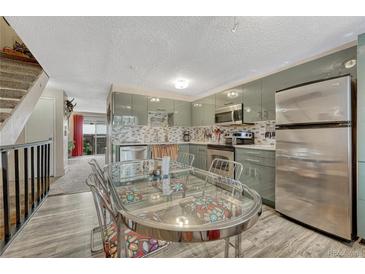 Modern kitchen features updated appliances, cabinets, and backsplash plus a glass top kitchen table with chairs at 14034 E Utah Cir, Aurora, CO 80012
