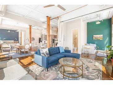 Bright and airy living room featuring exposed beams, hardwood floors, and a modern blue sectional at 1501 Wazee St # 4B, Denver, CO 80202