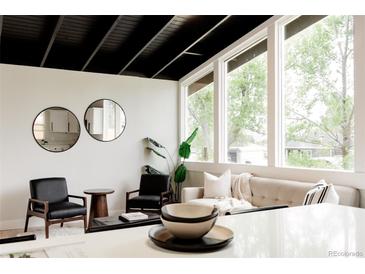 Bright living room with modern decor, black ceiling beams, and large windows with view at 7918 Raleigh Pl, Westminster, CO 80030