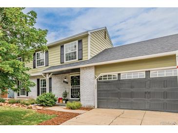 Two-story home featuring white brick, an attached garage, manicured shrubs, and a well-kept green lawn at 16051 E Alabama Dr, Aurora, CO 80017