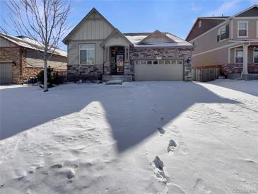 Charming home with a stone facade, attached garage, and snow-covered lawn at 1220 W 170Th Ave, Broomfield, CO 80023