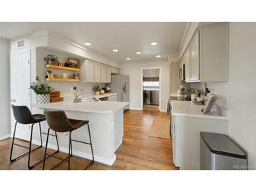 Updated kitchen with light-colored cabinets, quartz countertops, bar seating, and stainless steel appliances at 20000 Mitchell Pl # 9, Denver, CO 80249