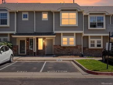 Charming townhome exterior with gray siding, stone accents, and visitor parking at sunset at 9024 Gale Blvd # 3, Thornton, CO 80260