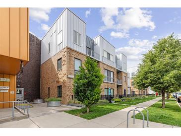 Modern multi-level condo building with brick facade, metal accents, and professional landscaping at 2550 Lawrence St # Rb306, Denver, CO 80205