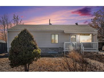 Charming single-story home with neutral siding, stone accents, and a cozy front porch under a beautiful sunset at 1940 E 95Th Ave, Thornton, CO 80229