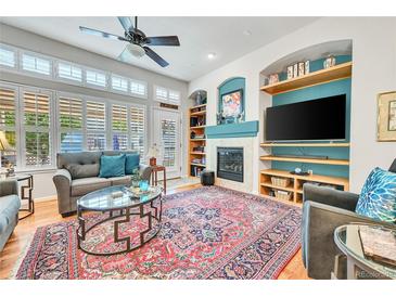 Cozy living room with a fireplace, built-in shelves, and large windows at 7193 S Versailles Way, Aurora, CO 80016