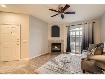 Cozy living room featuring a fireplace, modern ceiling fan, and sliding glass doors at 7440 S Blackhawk St # 4-104, Englewood, CO 80112