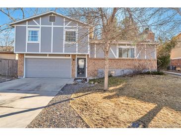 Charming home with a brick and siding facade, featuring a two-car garage and a well-manicured front yard at 13742 W 67Th Pl, Arvada, CO 80004