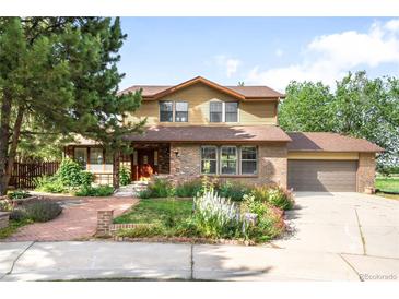 Charming two-story home with brick and siding exterior, lush landscaping, and attached two-car garage on a sunny day at 7603 W Coal Mine Pl, Littleton, CO 80128