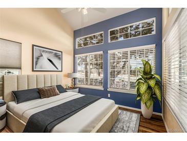 Bright bedroom featuring large windows, a cozy bed, and a stylish blue accent wall at 4084 S Carson St # A, Aurora, CO 80014