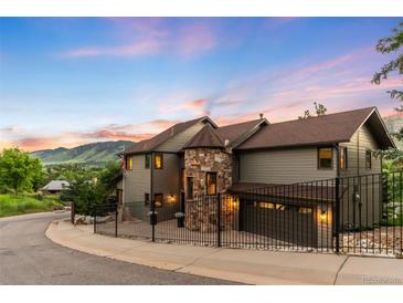 Stunning two-story home features a stone turret, fenced yard, and beautiful mountain views at sunset at 600 Cascade Dr, Golden, CO 80403