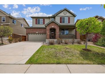 Charming two-story home features a well-manicured lawn, brick accents, and inviting front porch at 25466 E 4Th Pl, Aurora, CO 80018
