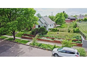 Charming home featuring a well-manicured lawn, flower beds, mature trees, and a quaint facade at 2809 Yates St, Denver, CO 80212