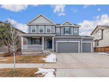 Two-story house with gray siding, a large front porch, and a two-car garage at 12243 Joplin St, Commerce City, CO 80603