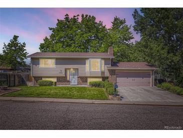 Charming two-story home with a well-maintained lawn, mature trees, and attached garage at 7331 S Webster St, Littleton, CO 80128