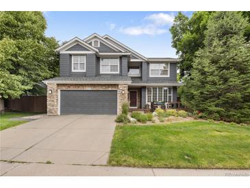 Charming two-story home with stone accents, gray siding, manicured lawn and two car garage at 2249 Weatherstone Cir, Highlands Ranch, CO 80126