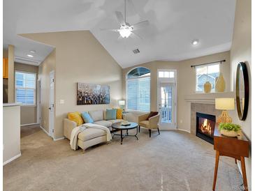 Bright living room with a cozy fireplace, high ceilings, and large windows at 1358 Carlyle Park Cir, Highlands Ranch, CO 80129