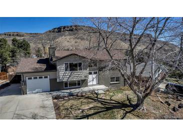 Charming exterior of a home with a two-car garage, landscaped yard, and backdrop of a large hill at 1003 N Jackson St, Golden, CO 80403