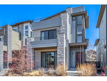 Modern three-story home with a stone facade, balcony, and a red front door at 6018 Beeler Ct, Denver, CO 80238