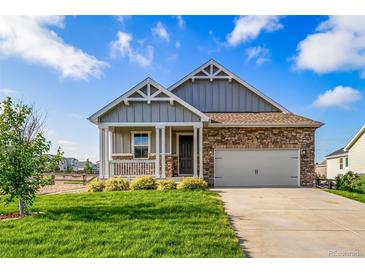 Charming home showcasing a stone facade, two-car garage, covered porch and manicured lawn on a bright day at 42400 Forest Oaks Dr, Elizabeth, CO 80107