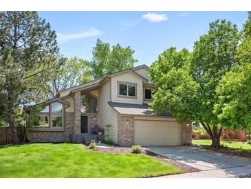 Charming two-story home with a well-manicured lawn, mature trees, and attached two car garage at 7582 Powderhorn Dr, Lone Tree, CO 80124
