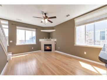 Inviting living room features a cozy fireplace, ceiling fan, and natural light from the windows at 8751 Pearl St # D1, Thornton, CO 80229