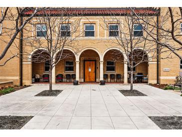 Inviting brick building featuring an arched entryway, seating, and a well-maintained walkway with new concrete at 2835 W Parkside Pl # 305, Denver, CO 80221