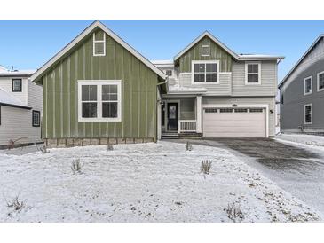 Charming two-story home with a green section, a lawn covered with snow, and an attached two car garage at 39877 Floyd St, Elizabeth, CO 80107