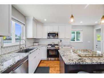 Bright kitchen features granite counters, stainless steel appliances, white cabinets, and hardwood floors at 6924 S Albion St, Centennial, CO 80122