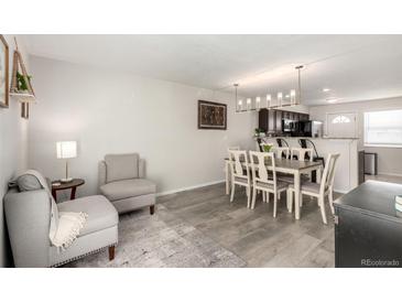 Bright living room featuring modern gray furniture and wood-look flooring adjacent to the dining area at 6450 Tennyson St # 1, Arvada, CO 80003