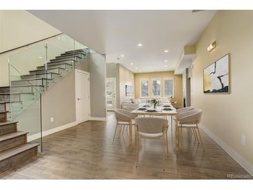 Open-concept dining area featuring sleek hardwood floors, contemporary lighting, and a modern glass-railing staircase at 2624 S Race St, Denver, CO 80210