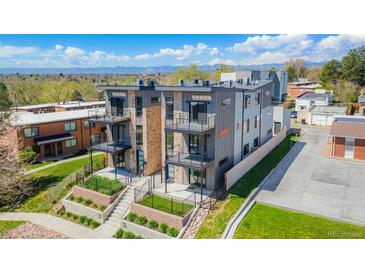 Modern townhome with gray siding, stone accents, and balconies in a landscaped community with mountain views at 1385 N King St, Denver, CO 80204