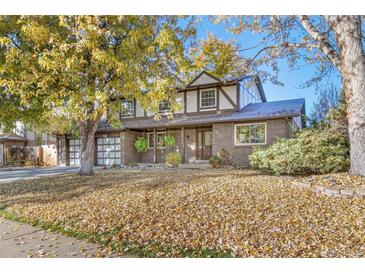 Charming two-story home with a brick facade and a well-manicured front yard covered in autumn leaves at 6827 Vivian St, Arvada, CO 80004