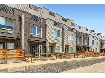 Modern townhomes with mixed brick and siding exteriors, complemented by wooden fences and rooftop decks against a clear blue sky at 3520 W Conejos Pl # 11, Denver, CO 80204