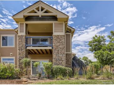 Condo exterior with stacked stone and siding, balcony, stairs, landscaping, and blue sky at 8726 S Kline St # A208, Littleton, CO 80127