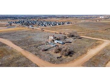 Expansive aerial view of a rural property featuring a charming home, outbuildings, and ample land near a residential community at 14624 County Road 12, Fort Lupton, CO 80621