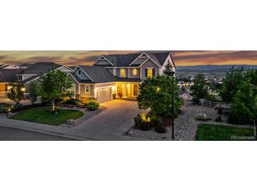 Charming two-story home with a well-manicured lawn, mature trees, and a paved driveway leading to a two-car garage at 696 Eveningsong Dr, Castle Rock, CO 80104