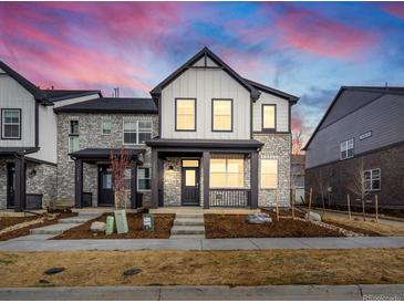 Two-story townhome with stone and white siding, welcoming porch, and landscaped yard at 22260 E 8Th Pl, Aurora, CO 80018