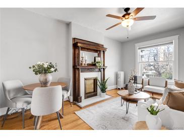 Inviting living room featuring a decorative fireplace, wood floors, ceiling fan, and a bright sitting area at 122 N Logan St, Denver, CO 80203