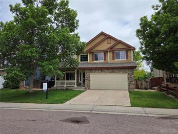 Two-story home with a stone facade, attached two-car garage, and a covered front porch at 8772 S Carr Way, Littleton, CO 80128
