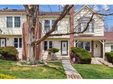Charming townhome with manicured lawn, mature trees, and brick accents on the exterior at 7665 S Steele St, Centennial, CO 80122