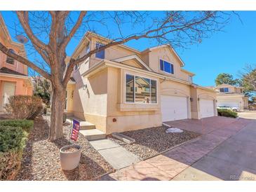 Charming exterior featuring stucco siding, attached garage, and manicured front yard, complemented by a mature tree at 12420 E Iliff Pl, Aurora, CO 80014