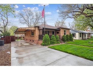 Charming brick home featuring a well-manicured lawn, covered carport, and an inviting front porch at 2989 S Corona St, Englewood, CO 80113