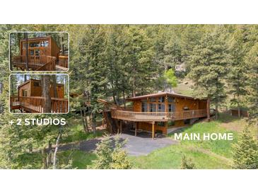Scenic home with a large deck and wood accents surrounded by lush greenery and mature trees at 4923 Snowberry Ln, Evergreen, CO 80439