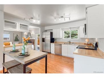 Bright kitchen features stainless steel appliances, butcher block countertops, and a breakfast nook with modern lighting at 602 Birch St, Broomfield, CO 80020