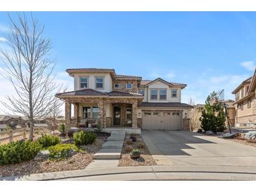 Beautiful two-story home with stone and stucco exterior, landscaped front yard and three car garage at 1240 Starglow Pl, Highlands Ranch, CO 80126