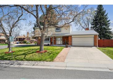 Charming two-story home features a well-maintained lawn, mature tree, and attached two-car garage at 8201 Allison Ct, Arvada, CO 80005