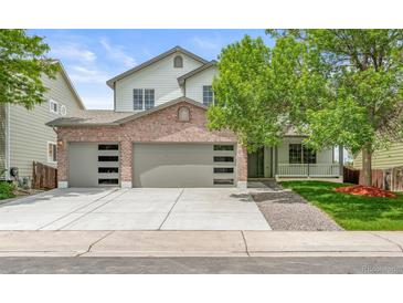 Charming two-story home featuring a brick facade, three-car garage, and a well-manicured front lawn at 11383 Oakland Dr, Commerce City, CO 80640