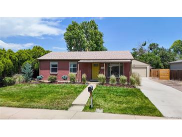 Charming brick home with a well-maintained lawn, lush landscaping, and a detached garage at 1741 W 55Th Pl, Denver, CO 80221